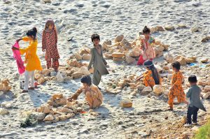 Children are enjoying playing with stone at dry area of Indus River
