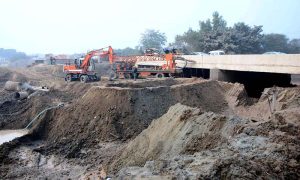 Workers are busy in construction work during the extension of the Sikandari Nala Bridge on Head Muhammad Wala Road as part of an ongoing development project.