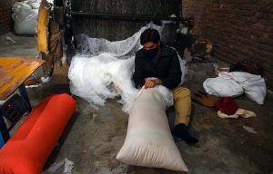 A laborer is busy filling pillows at a factory in Dabgari Garden.