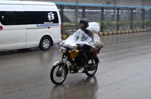 motorcyclist covered himself with a plastic sheet to protect from rain that experienced in the Provincial Capital.