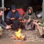Vendors gather around a fire to keep warm in the Peshawar Fruit Market as the city's temperature drops below freezing.