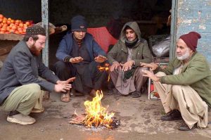 Vendors gather around a fire to keep warm in the Peshawar Fruit Market as the city's temperature drops below freezing.