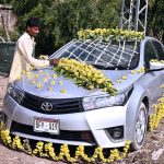 A worker decorates a car for a wedding on Qasimabad Road