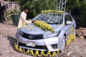 A worker decorates a car for a wedding on Qasimabad Road