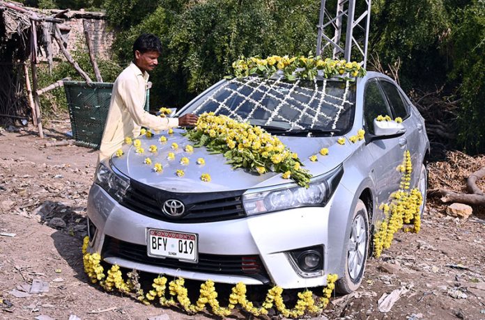 A worker decorates a car for a wedding on Qasimabad Road