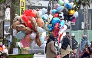 An elderly vendor displaying balloons and cotton candy to attract the customers in a local market.