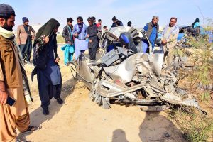 People gather around a damaged car after a truck-car collision on Kotri-Thatta Road, in which eight people died
