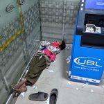 A gypsy young boy naps inside a bank's ATM booth to escape the cold on Railway Station Road.