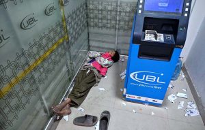A gypsy young boy naps inside a bank's ATM booth to escape the cold on Railway Station Road.
