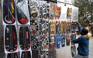 A vendor displays various plastic stickers for motorcycles along a roadside in the city