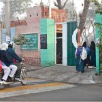 Students walk through the school gates with backpacks as classes resume on the first day after winter vacations in the city.