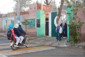 Students walk through the school gates with backpacks as classes resume on the first day after winter vacations in the city.