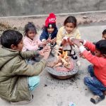 Children warm themselves by a fire to stay safe from the extremely cold weather