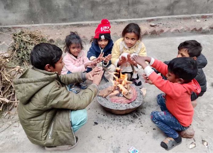 Children warm themselves by a fire to stay safe from the extremely cold weather
