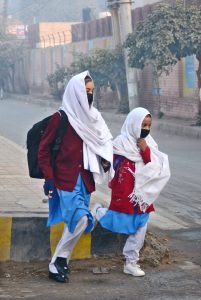 Students walk through the school gates with backpacks as classes resume on the first day after winter vacations in the city.