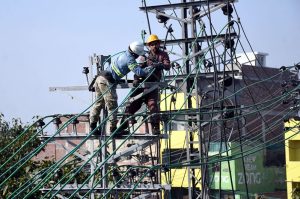 WAPDA workers install new electric transmission wires on a pylon to upgrade the power network