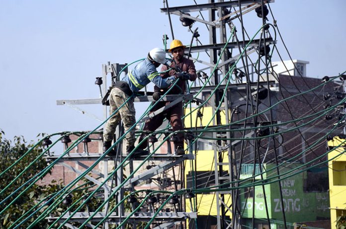WAPDA workers install new electric transmission wires on a pylon to upgrade the power network