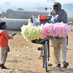 A street vendor on the way along with his bicycle loaded with cotton candy at Latifabad