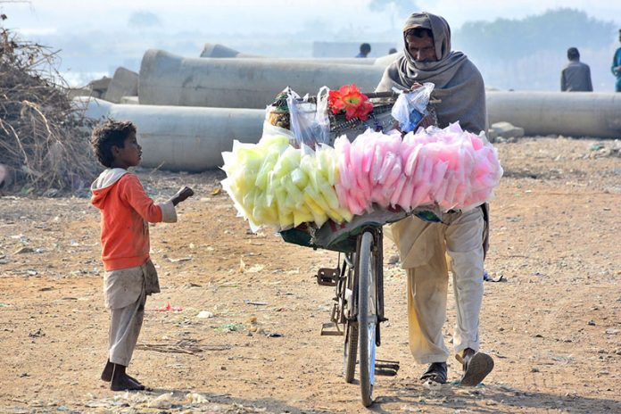 A street vendor on the way along with his bicycle loaded with cotton candy at Latifabad