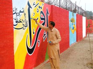 An artist paints calligraphy on the walls of a government school.