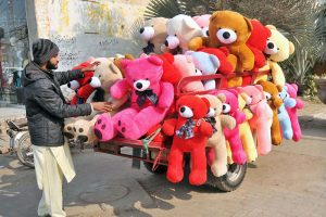 A roadside vendor displays colorful teddy bears loaded on a motorcycle trolley to attract customers