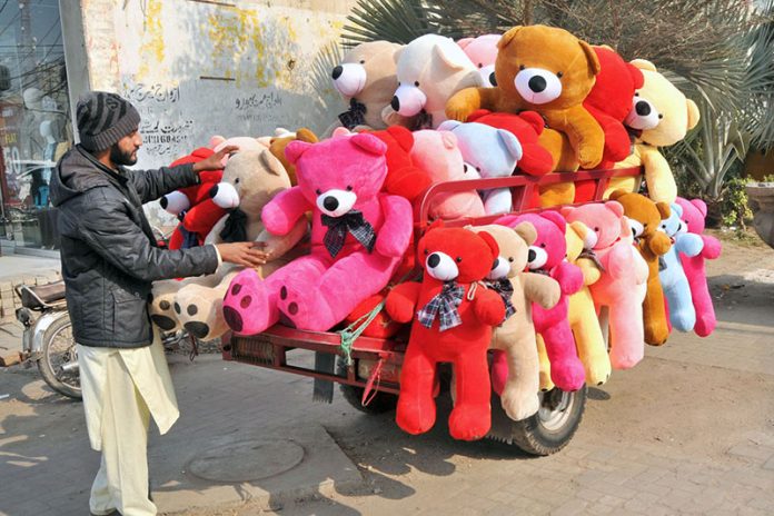 A roadside vendor displays colorful teddy bears loaded on a motorcycle trolley to attract customers