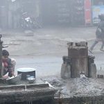 A worker washing utensils in front of a local hotel during cold weather at Canal Road.