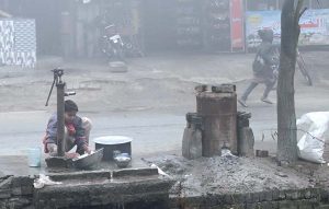 A worker washing utensils in front of a local hotel during cold weather at Canal Road.