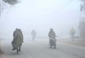 A worker washing utensils in front of a local hotel during cold weather at Canal Road.