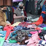 Women busy selecting and purchasing second hand warm clothes from vendor in weekly bazaar in the Federal Capital
