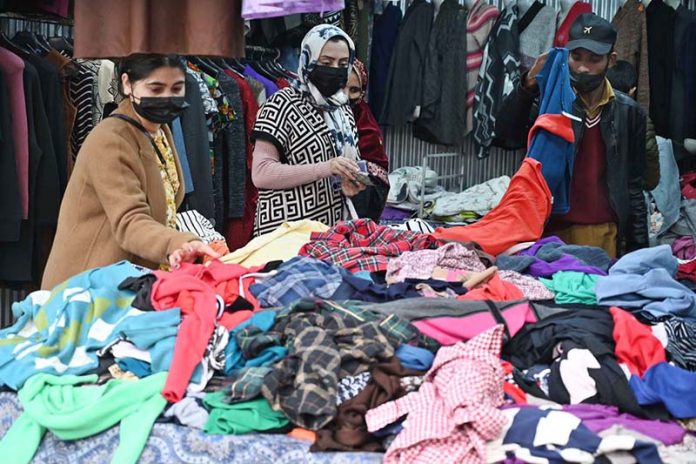 Women busy selecting and purchasing second hand warm clothes from vendor in weekly bazaar in the Federal Capital