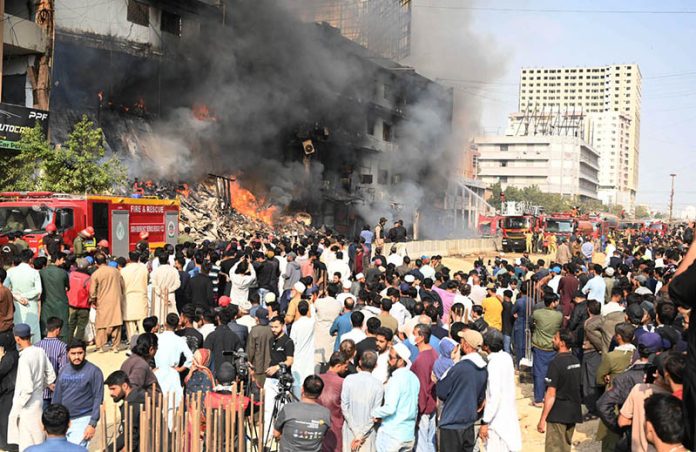 A view of Fire erupted last night at Gul Plaza shopping mall, and efforts to extinguish the massive blaze are still ongoing. Meanwhile, traders and their relatives are seen looking at the burnt mall