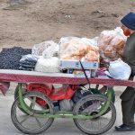 A vendor pushing handcart loaded with edible items to attract the customers