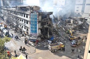 Rescue workers work with heavy machinery to clear the rubble of a burnt building of a multi-story Gul shopping plaza following a massive fire.