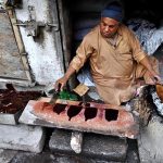 A worker prepares wooden polish for furniture at his workplace outside Mori Gate in the provincial capital.