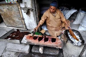 A worker prepares wooden polish for furniture at his workplace outside Mori Gate in the provincial capital.