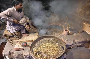 A worker busy in roasting grams for customers at his workplace in the Provincial Capital.