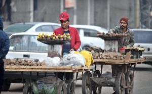 A vendor pushing handcart loaded with edible items to attract the customers