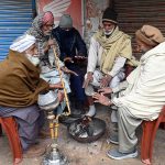 In the severe cold of the provincial capital, elderly people warm their hands by a fire and enjoy a traditional hookah at Chowk Noonarian, Khuda Bakhsh Road