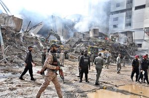 Rescue workers work with heavy machinery to clear the rubble of a burnt building of a multi-story Gul shopping plaza following a massive fire.