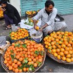 A vendor washes and cleans citrus fruits for sale at a roadside his setup outside Mori Gate in the provincial capital.