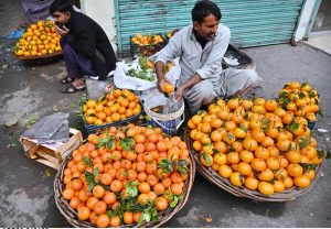 A vendor washes and cleans citrus fruits for sale at a roadside his setup outside Mori Gate in the provincial capital.