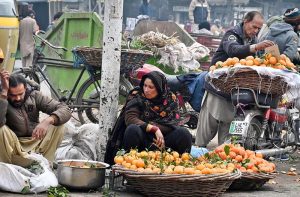 A vendor washes and cleans citrus fruits for sale at a roadside his setup outside Mori Gate in the provincial capital.