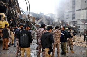 Rescue workers work with heavy machinery to clear the rubble of a burnt building of a multi-story Gul shopping plaza following a massive fire.