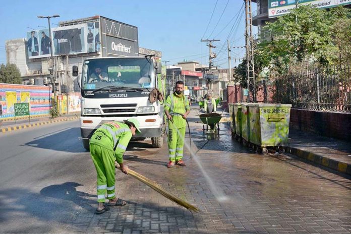Faisalabad Waste Management Company (FWMC) workers wash a roadway with water as part of the ongoing Clean Punjab campaign in the city