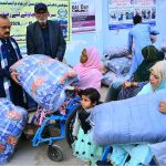 President of Sohni Dharti Youth Council, Mukhtiyar Ahmad, distributes quilts among disabled women and persons during a winter relief program at a disabled persons center