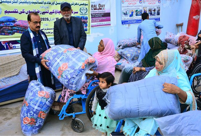 President of Sohni Dharti Youth Council, Mukhtiyar Ahmad, distributes quilts among disabled women and persons during a winter relief program at a disabled persons center