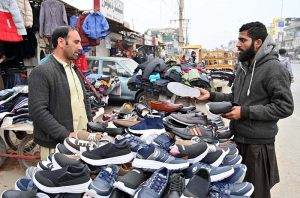 A man buying shoes from a roadside vendor.