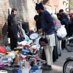 People selecting and purchasing used items from a stall along Mall Road in Provincial Capital