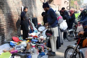 People selecting and purchasing used items from a stall along Mall Road in Provincial Capital